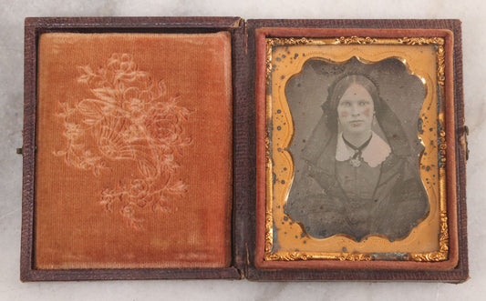 Lot 015 - Antique 1/9th Plate Daguerreotype Photograph Of Young Woman With Striking Eyes, White Collar, And Bonnet With Long Dark Lappets, In Full Intact Leatherette Union Case With Rose Motif