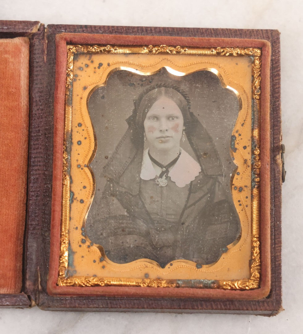 Lot 015 - Antique 1/9th Plate Daguerreotype Photograph Of Young Woman With Striking Eyes, White Collar, And Bonnet With Long Dark Lappets, In Full Intact Leatherette Union Case With Rose Motif