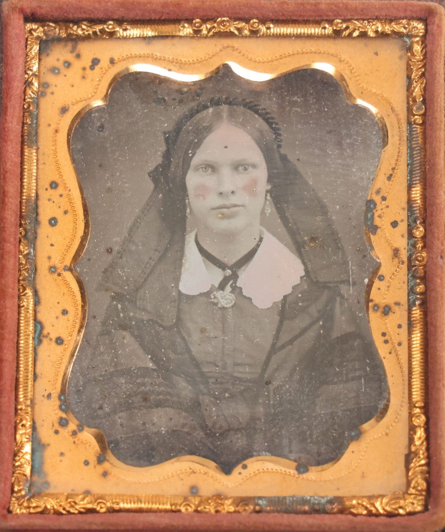 Lot 015 - Antique 1/9th Plate Daguerreotype Photograph Of Young Woman With Striking Eyes, White Collar, And Bonnet With Long Dark Lappets, In Full Intact Leatherette Union Case With Rose Motif
