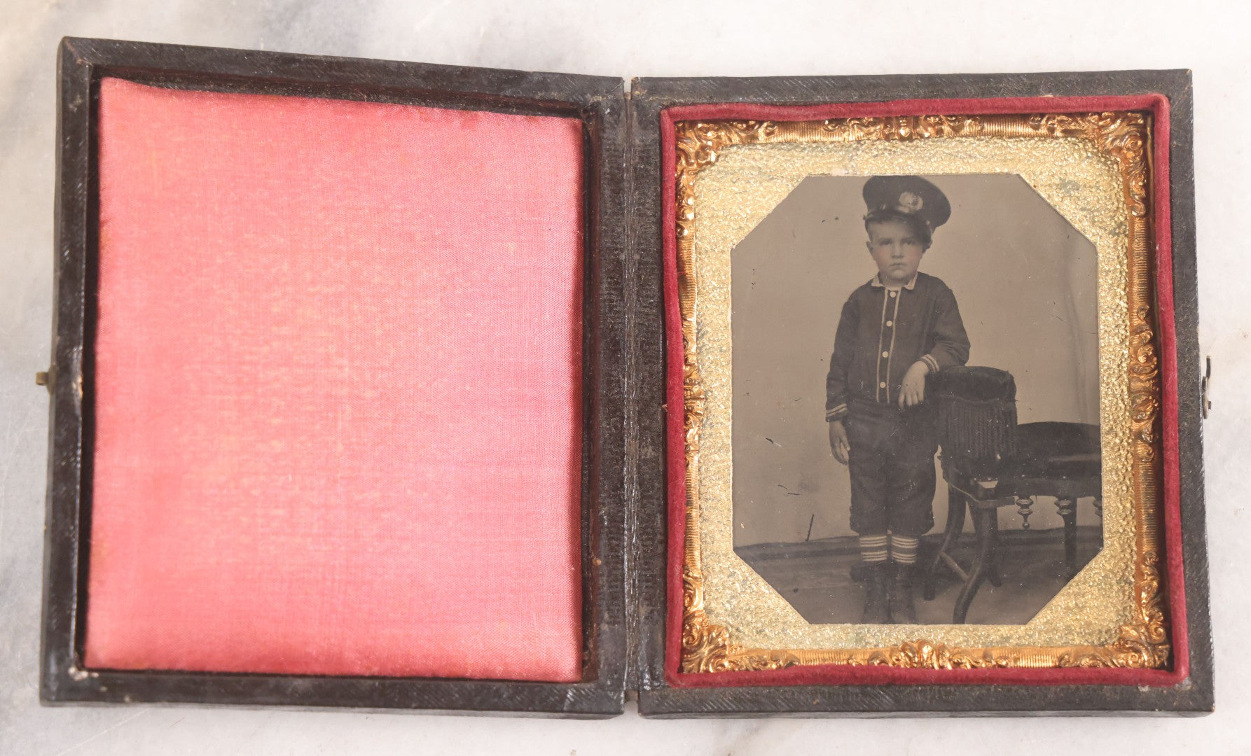 Lot 016 - Antique 1/6th Plate Tintype Photograph Of Young Boy Wearing Military Style Hat And Leaning Against Chair, In Full Intact Leatherette Union Case