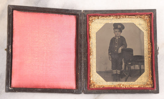 Lot 016 - Antique 1/6th Plate Tintype Photograph Of Young Boy Wearing Military Style Hat And Leaning Against Chair, In Full Intact Leatherette Union Case