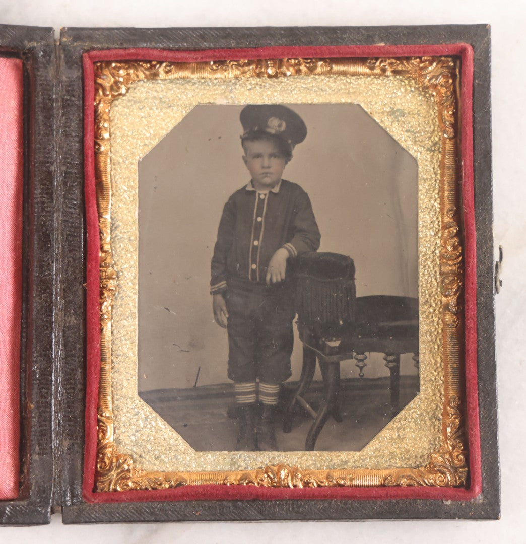 Lot 016 - Antique 1/6th Plate Tintype Photograph Of Young Boy Wearing Military Style Hat And Leaning Against Chair, In Full Intact Leatherette Union Case