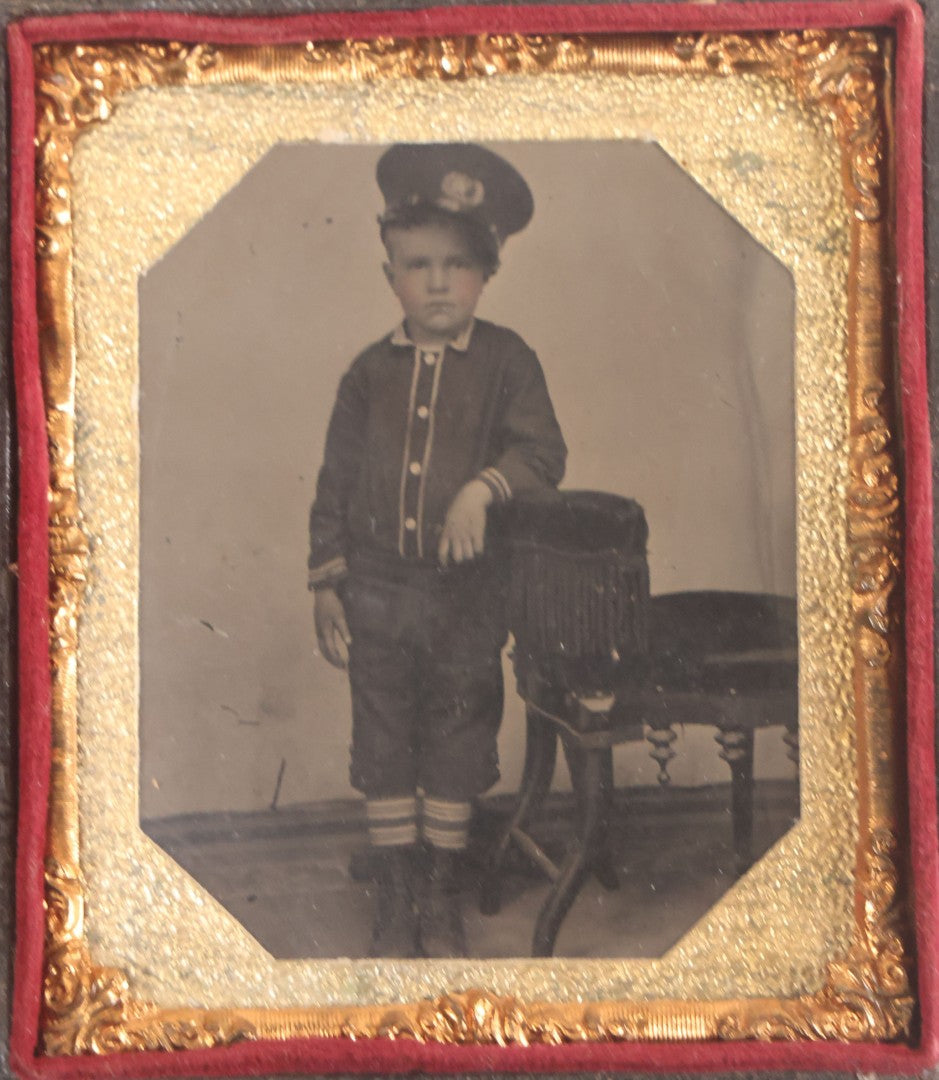 Lot 016 - Antique 1/6th Plate Tintype Photograph Of Young Boy Wearing Military Style Hat And Leaning Against Chair, In Full Intact Leatherette Union Case