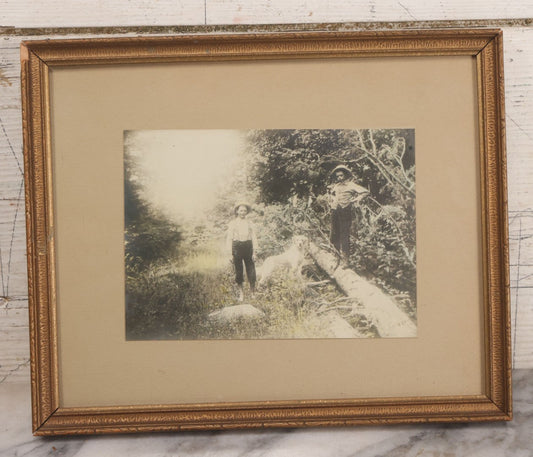 Lot 055 - Antique Green Tinted Black And White Photograph Of Two Boys Posing With Their Yellow Labrador Retriever Dog In The Woods, In Frame, 10-5/8" x 8-3/4"