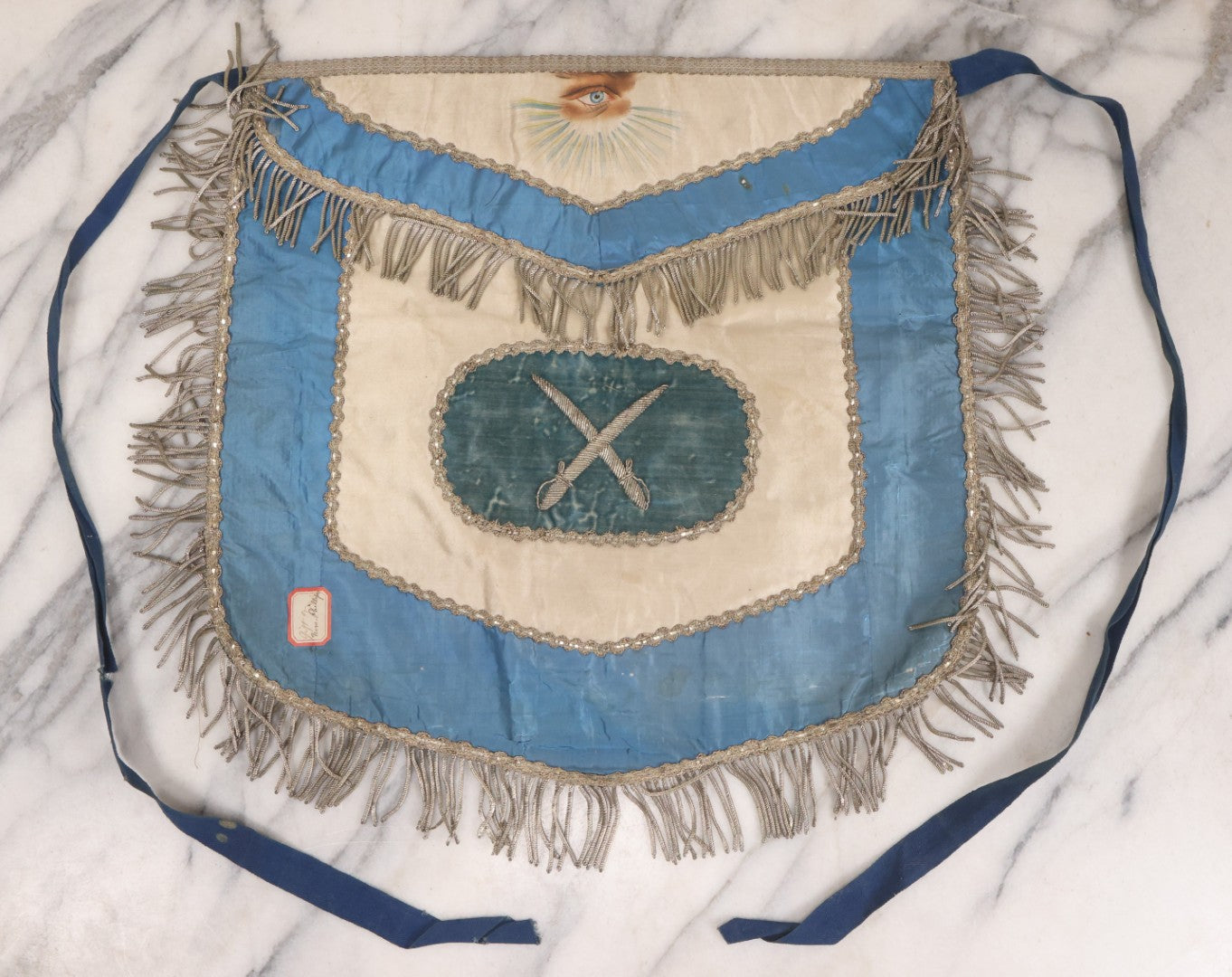 Lot 010 - Antique Odd Fellows I.O.O.F. Fraternal Apron With Embroidered Crossed Swords And Hand Painted All-Seeing-Eye Motifs, Silver Toned Fringe, Blue Coloring