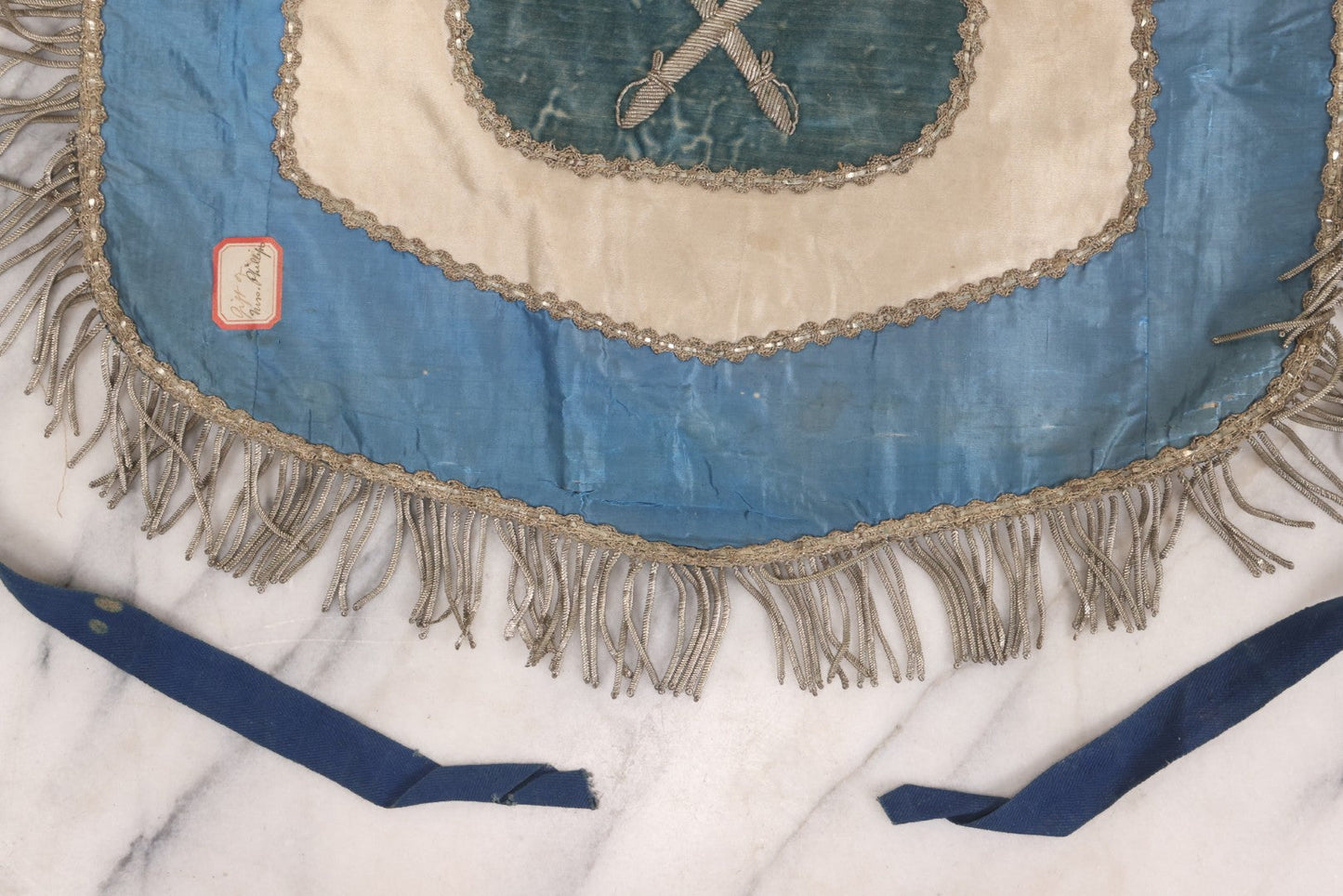 Lot 010 - Antique Odd Fellows I.O.O.F. Fraternal Apron With Embroidered Crossed Swords And Hand Painted All-Seeing-Eye Motifs, Silver Toned Fringe, Blue Coloring