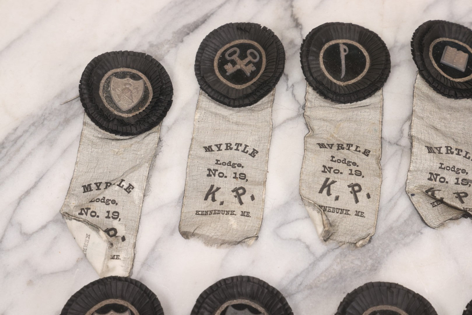 Lot 013 - Grouping Of 15+ Antique Knights Of Pythias Fraternal Badges And Ribbons With Black Coloring, White Ribbons With Black Veil Covering, Pressed Metal Insignia, Myrtle Lodge No. 19, K.P., Kennebunk, Maine