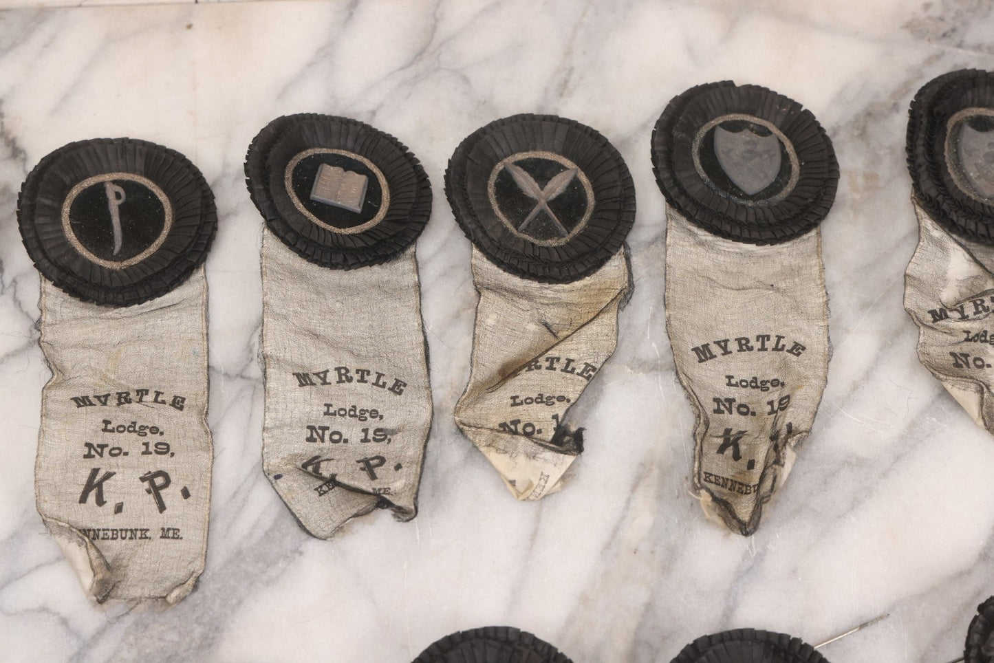 Lot 013 - Grouping Of 15+ Antique Knights Of Pythias Fraternal Badges And Ribbons With Black Coloring, White Ribbons With Black Veil Covering, Pressed Metal Insignia, Myrtle Lodge No. 19, K.P., Kennebunk, Maine