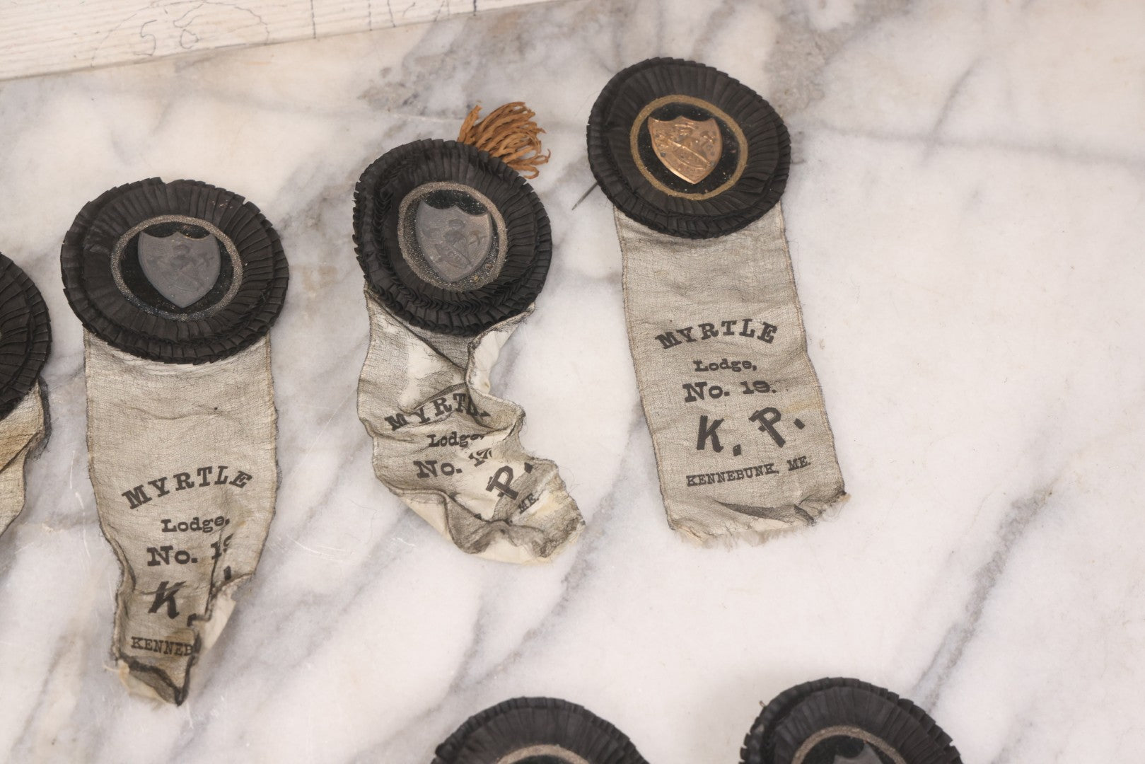 Lot 013 - Grouping Of 15+ Antique Knights Of Pythias Fraternal Badges And Ribbons With Black Coloring, White Ribbons With Black Veil Covering, Pressed Metal Insignia, Myrtle Lodge No. 19, K.P., Kennebunk, Maine