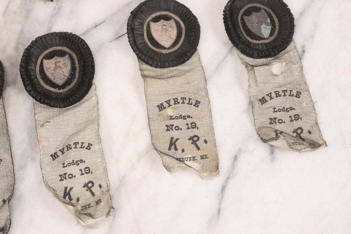 Lot 013 - Grouping Of 15+ Antique Knights Of Pythias Fraternal Badges And Ribbons With Black Coloring, White Ribbons With Black Veil Covering, Pressed Metal Insignia, Myrtle Lodge No. 19, K.P., Kennebunk, Maine