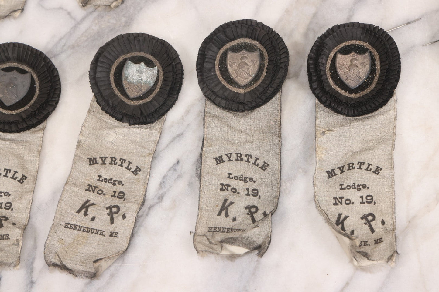 Lot 013 - Grouping Of 15+ Antique Knights Of Pythias Fraternal Badges And Ribbons With Black Coloring, White Ribbons With Black Veil Covering, Pressed Metal Insignia, Myrtle Lodge No. 19, K.P., Kennebunk, Maine