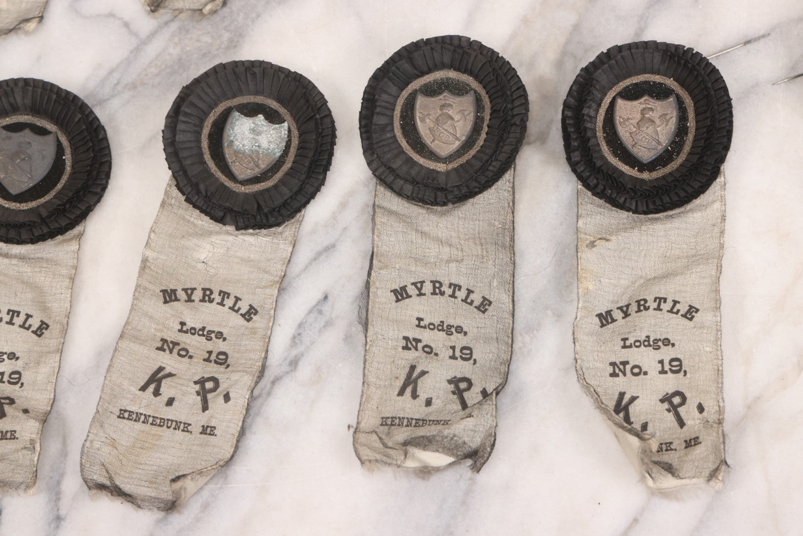 Lot 013 - Grouping Of 15+ Antique Knights Of Pythias Fraternal Badges And Ribbons With Black Coloring, White Ribbons With Black Veil Covering, Pressed Metal Insignia, Myrtle Lodge No. 19, K.P., Kennebunk, Maine