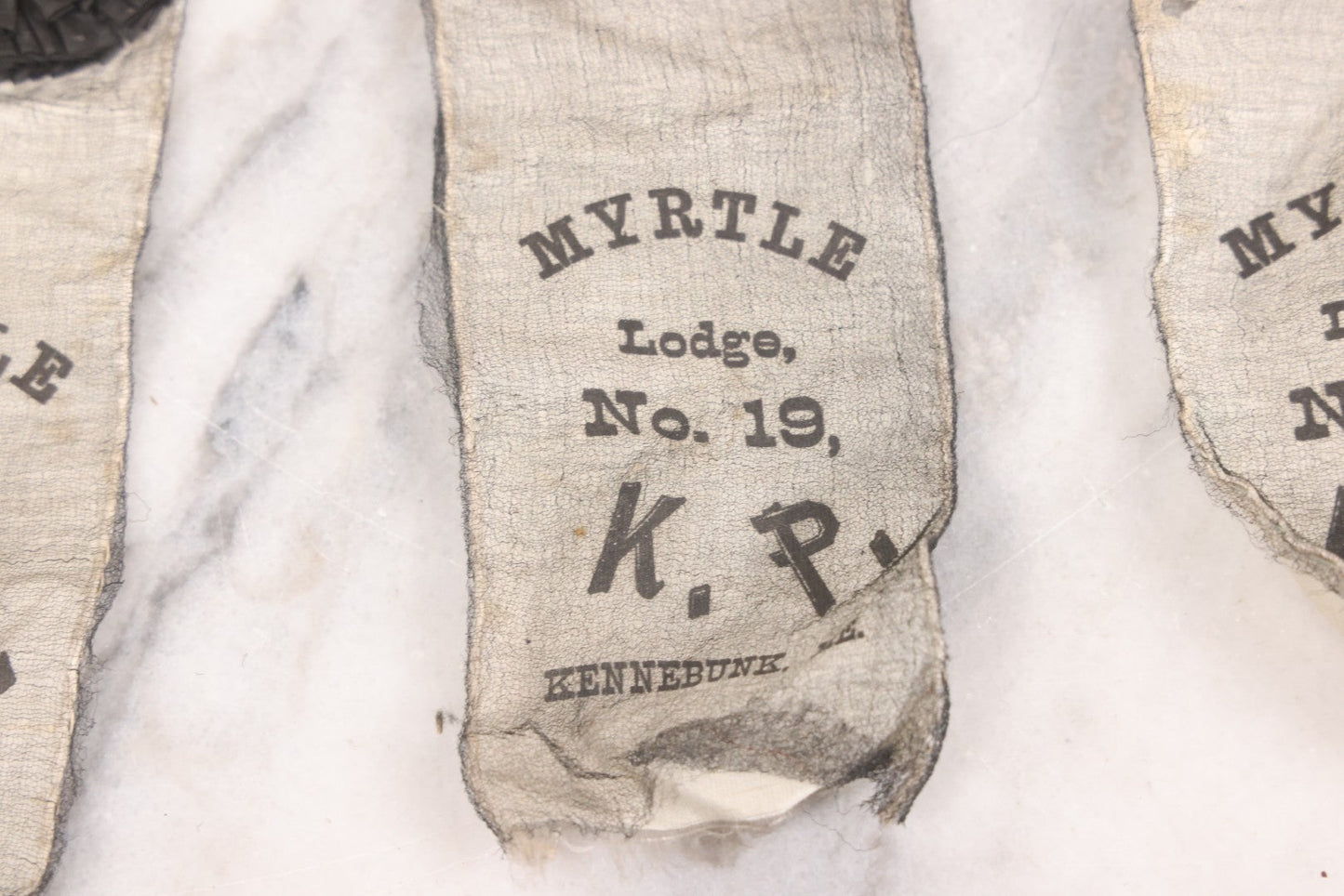 Lot 013 - Grouping Of 15+ Antique Knights Of Pythias Fraternal Badges And Ribbons With Black Coloring, White Ribbons With Black Veil Covering, Pressed Metal Insignia, Myrtle Lodge No. 19, K.P., Kennebunk, Maine