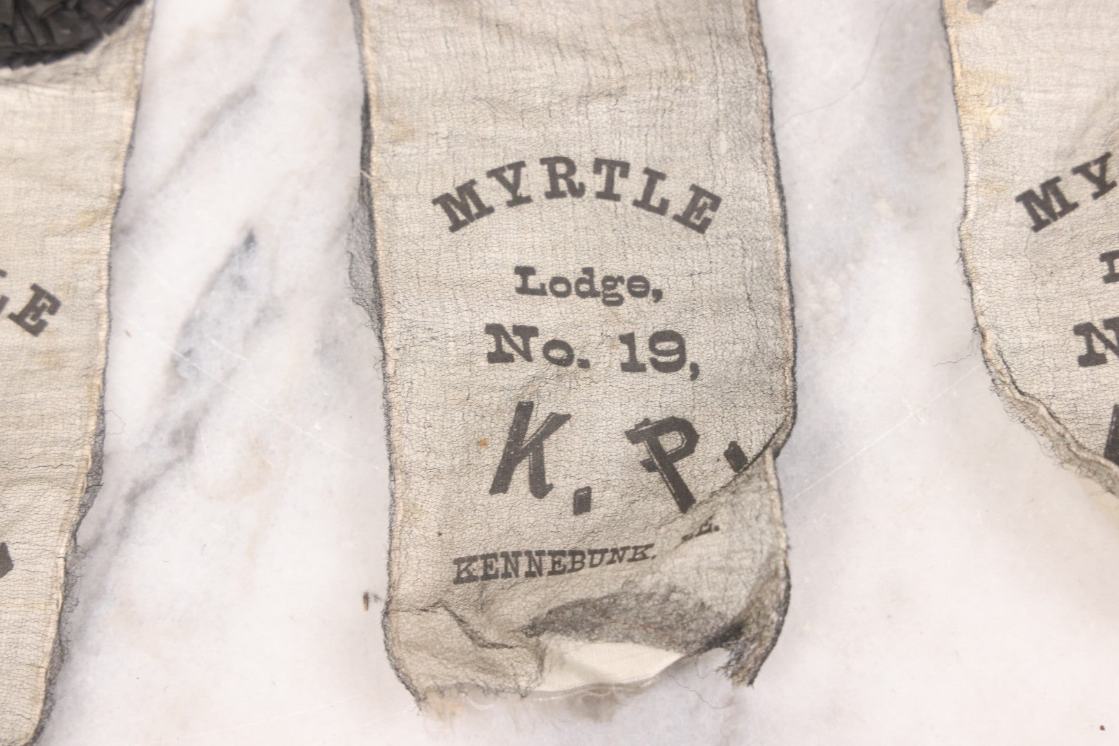 Lot 013 - Grouping Of 15+ Antique Knights Of Pythias Fraternal Badges And Ribbons With Black Coloring, White Ribbons With Black Veil Covering, Pressed Metal Insignia, Myrtle Lodge No. 19, K.P., Kennebunk, Maine