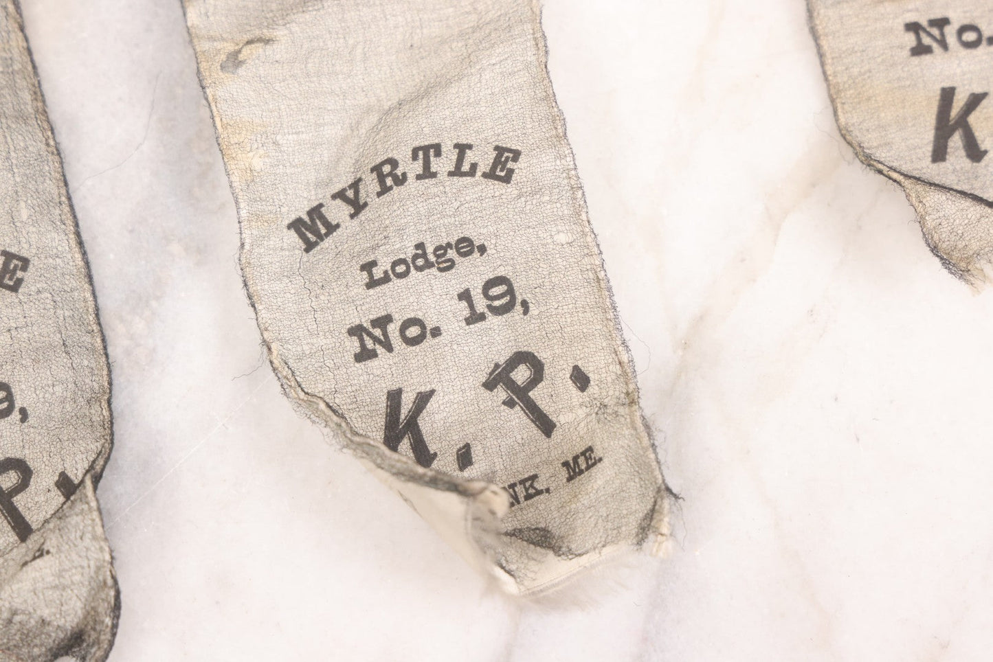 Lot 013 - Grouping Of 15+ Antique Knights Of Pythias Fraternal Badges And Ribbons With Black Coloring, White Ribbons With Black Veil Covering, Pressed Metal Insignia, Myrtle Lodge No. 19, K.P., Kennebunk, Maine