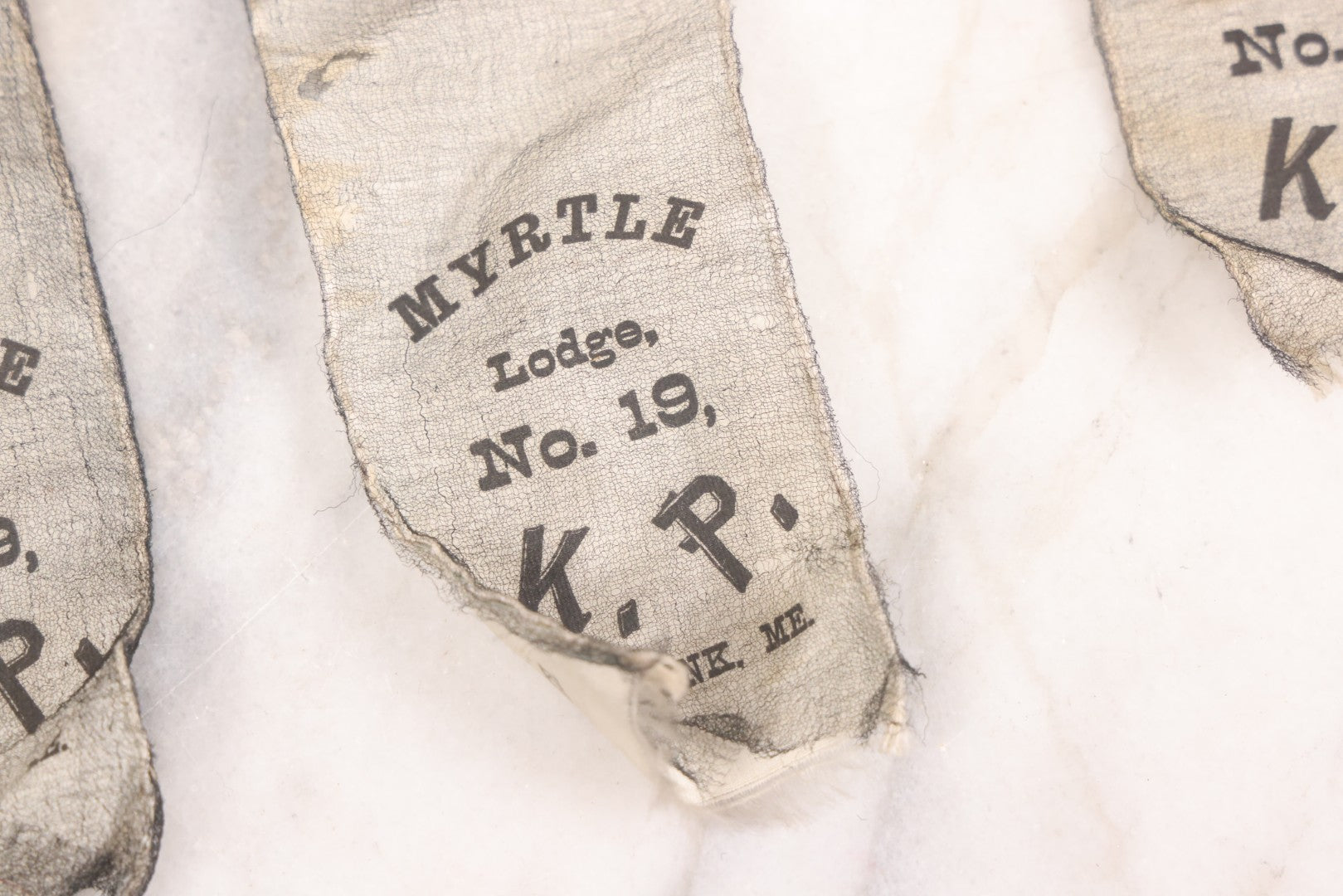 Lot 013 - Grouping Of 15+ Antique Knights Of Pythias Fraternal Badges And Ribbons With Black Coloring, White Ribbons With Black Veil Covering, Pressed Metal Insignia, Myrtle Lodge No. 19, K.P., Kennebunk, Maine