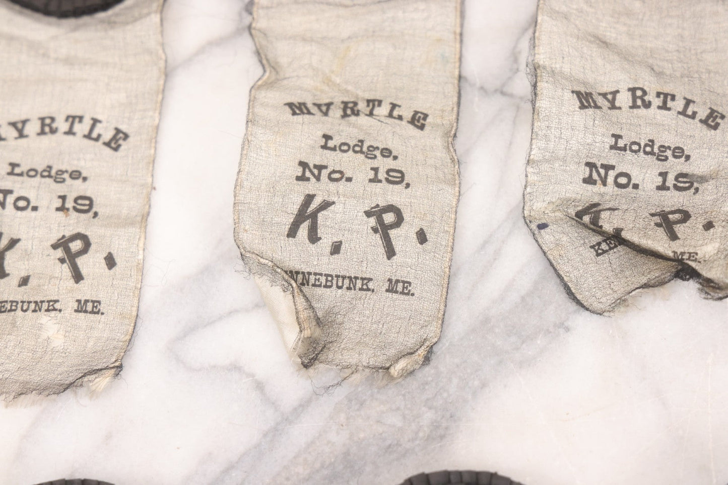 Lot 013 - Grouping Of 15+ Antique Knights Of Pythias Fraternal Badges And Ribbons With Black Coloring, White Ribbons With Black Veil Covering, Pressed Metal Insignia, Myrtle Lodge No. 19, K.P., Kennebunk, Maine