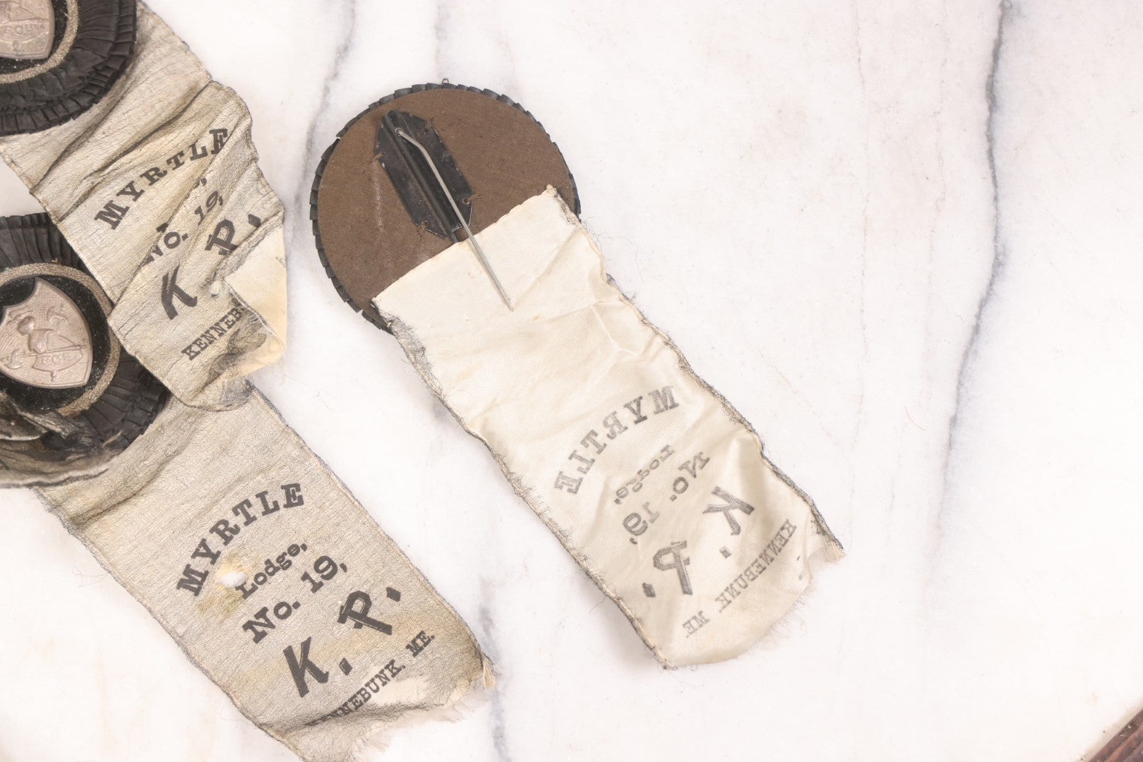 Lot 013 - Grouping Of 15+ Antique Knights Of Pythias Fraternal Badges And Ribbons With Black Coloring, White Ribbons With Black Veil Covering, Pressed Metal Insignia, Myrtle Lodge No. 19, K.P., Kennebunk, Maine