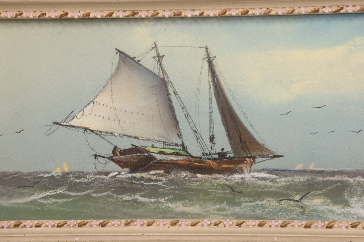 Lot 024 - Antique Nautical Pastel Painting Of A Sailing Ship On Choppy Waters, With Coastal Mountains, Other Ships In Background, Artist Signed M. Dulmy, In Original Painted Pressed Gesso Custom Frame, 23" x 9"