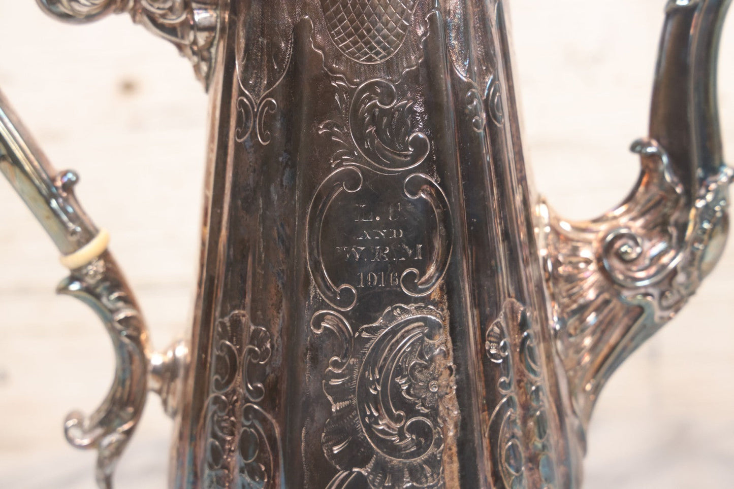 Lot 069 - Antique Embellished And Etched Silverplate Teapot With Hinged Lid And Handle With Bone Fittings, With Floral, Scroll And Pineapple Motifs, Engraved L.C. And W. R. M. 1916, 10-1/2" Height