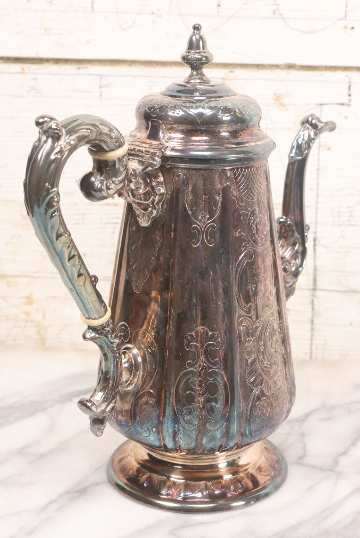 Lot 069 - Antique Embellished And Etched Silverplate Teapot With Hinged Lid And Handle With Bone Fittings, With Floral, Scroll And Pineapple Motifs, Engraved L.C. And W. R. M. 1916, 10-1/2" Height