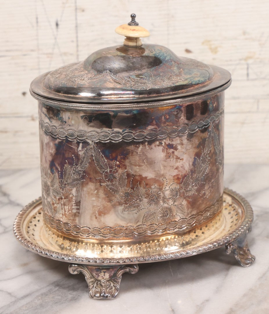 Lot 070 - Antique Etched Silverplate Single Piece Lidded Jar With Hinged Lid And Bone Handle On Slotted Tray With Feet, With Flower And Leaf Wreaths And Rope Twist Motifs, Marked J. E. & S. Ltd., Made In England, 7-1/2" Height