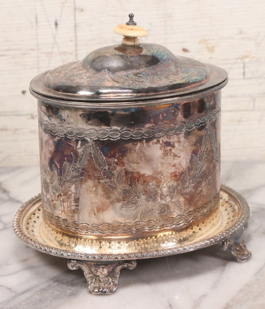 Lot 070 - Antique Etched Silverplate Single Piece Lidded Jar With Hinged Lid And Bone Handle On Slotted Tray With Feet, With Flower And Leaf Wreaths And Rope Twist Motifs, Marked J. E. & S. Ltd., Made In England, 7-1/2" Height