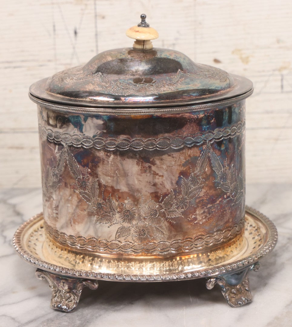 Lot 070 - Antique Etched Silverplate Single Piece Lidded Jar With Hinged Lid And Bone Handle On Slotted Tray With Feet, With Flower And Leaf Wreaths And Rope Twist Motifs, Marked J. E. & S. Ltd., Made In England, 7-1/2" Height