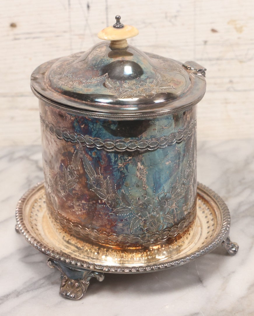 Lot 070 - Antique Etched Silverplate Single Piece Lidded Jar With Hinged Lid And Bone Handle On Slotted Tray With Feet, With Flower And Leaf Wreaths And Rope Twist Motifs, Marked J. E. & S. Ltd., Made In England, 7-1/2" Height