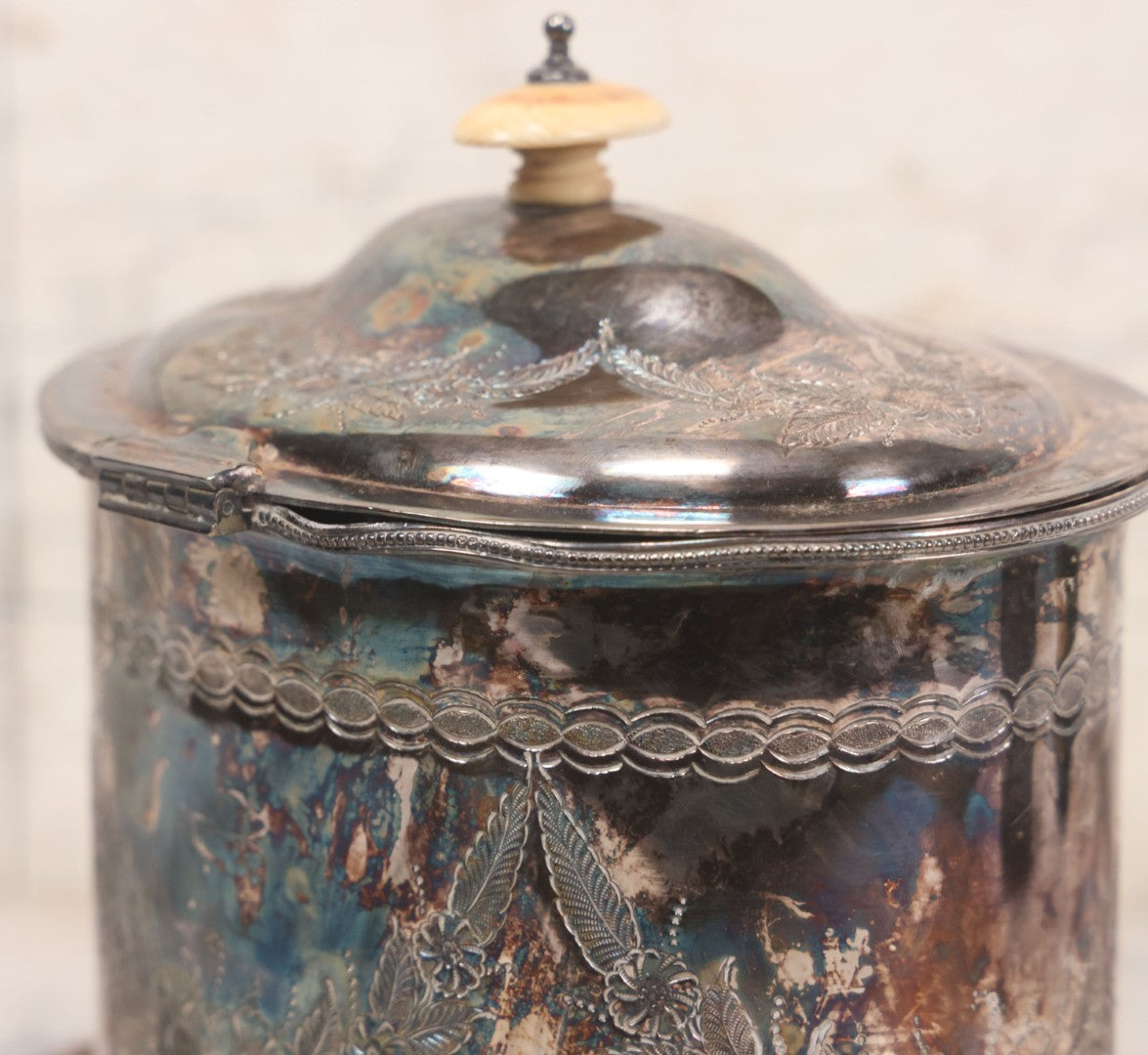 Lot 070 - Antique Etched Silverplate Single Piece Lidded Jar With Hinged Lid And Bone Handle On Slotted Tray With Feet, With Flower And Leaf Wreaths And Rope Twist Motifs, Marked J. E. & S. Ltd., Made In England, 7-1/2" Height