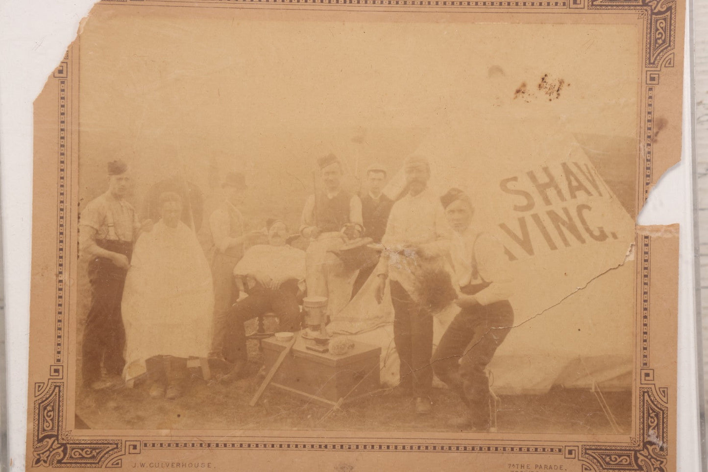 Lot 083 - Antique Boarded Photograph Of Soldier's Shaving Tent With Men Posing With Rifles, Barber, Implements And Tools, Photo By J.W. Culverhouse, " 7A The Parade, Trowbridge" Wiltshire, England, Note Photo Damaged, Losses