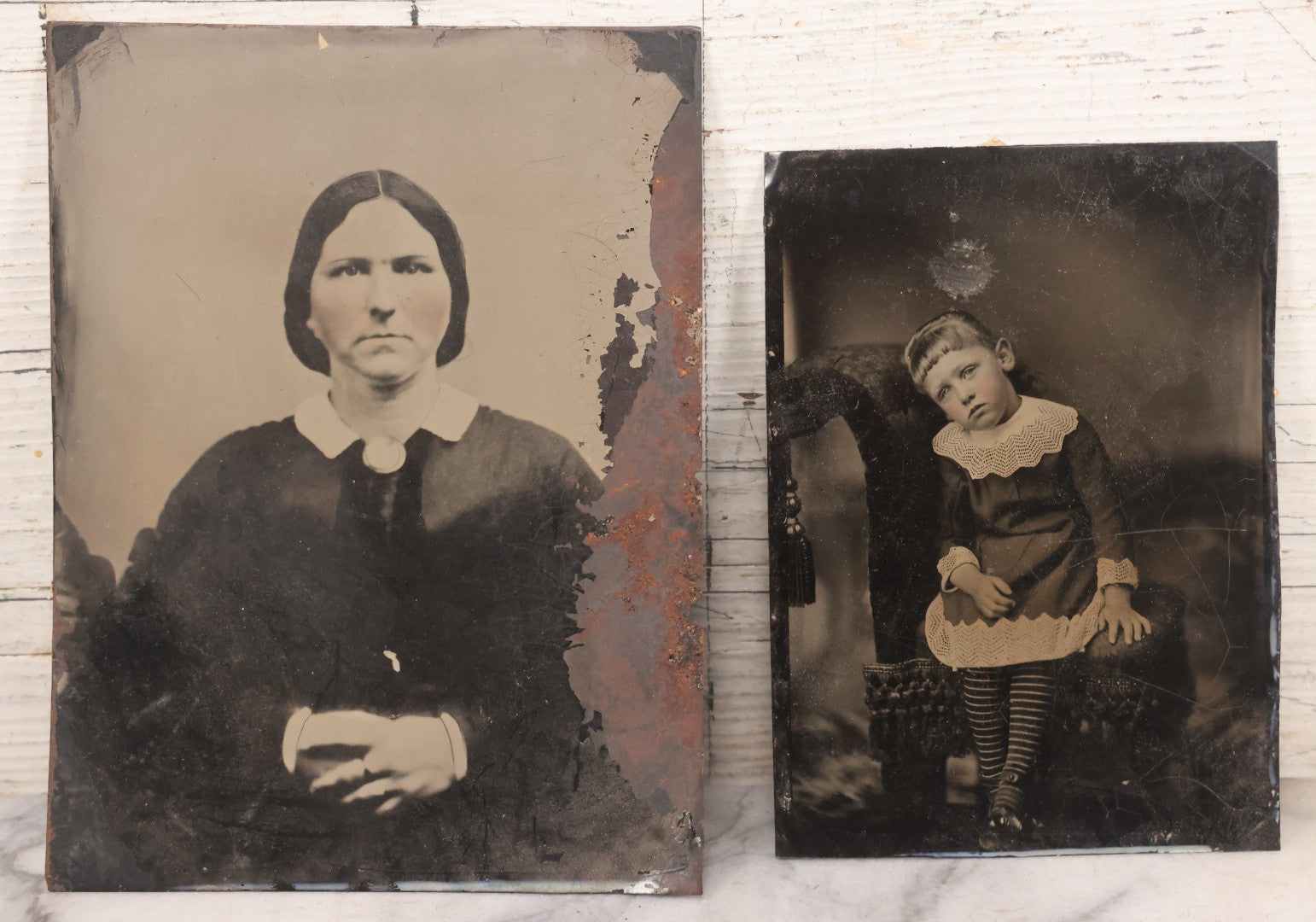 Lot 085 - Pair Of Antique Tintype Photographs Including Half Plate Tintype Of A Young Girl With Striped Socks And A Full Plate Tintype Of A Serious Looking Woman With Folded Hands