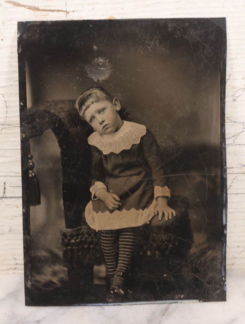 Lot 085 - Pair Of Antique Tintype Photographs Including Half Plate Tintype Of A Young Girl With Striped Socks And A Full Plate Tintype Of A Serious Looking Woman With Folded Hands