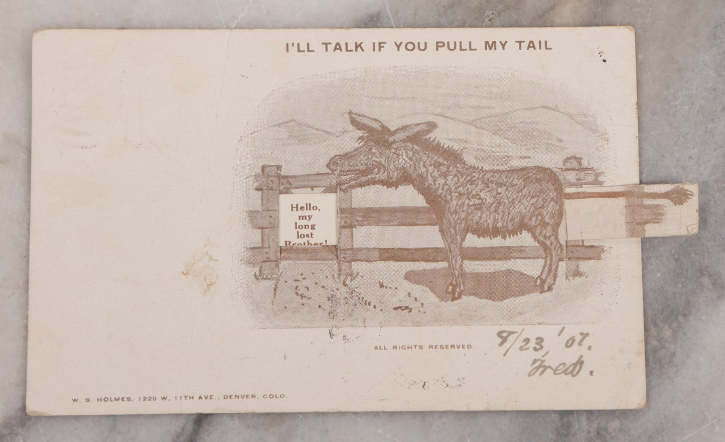 Lot 123 - Single Antique Mechanical Paper Postcard, Donkey, "I'll Talk If You Pull My Tail," Pulling Tail Reveals Message, "Hello My Long Lost Brother," W.S. Holmes, Publisher, Denver, Colorado, Signed Fred, 1907, Postmarked