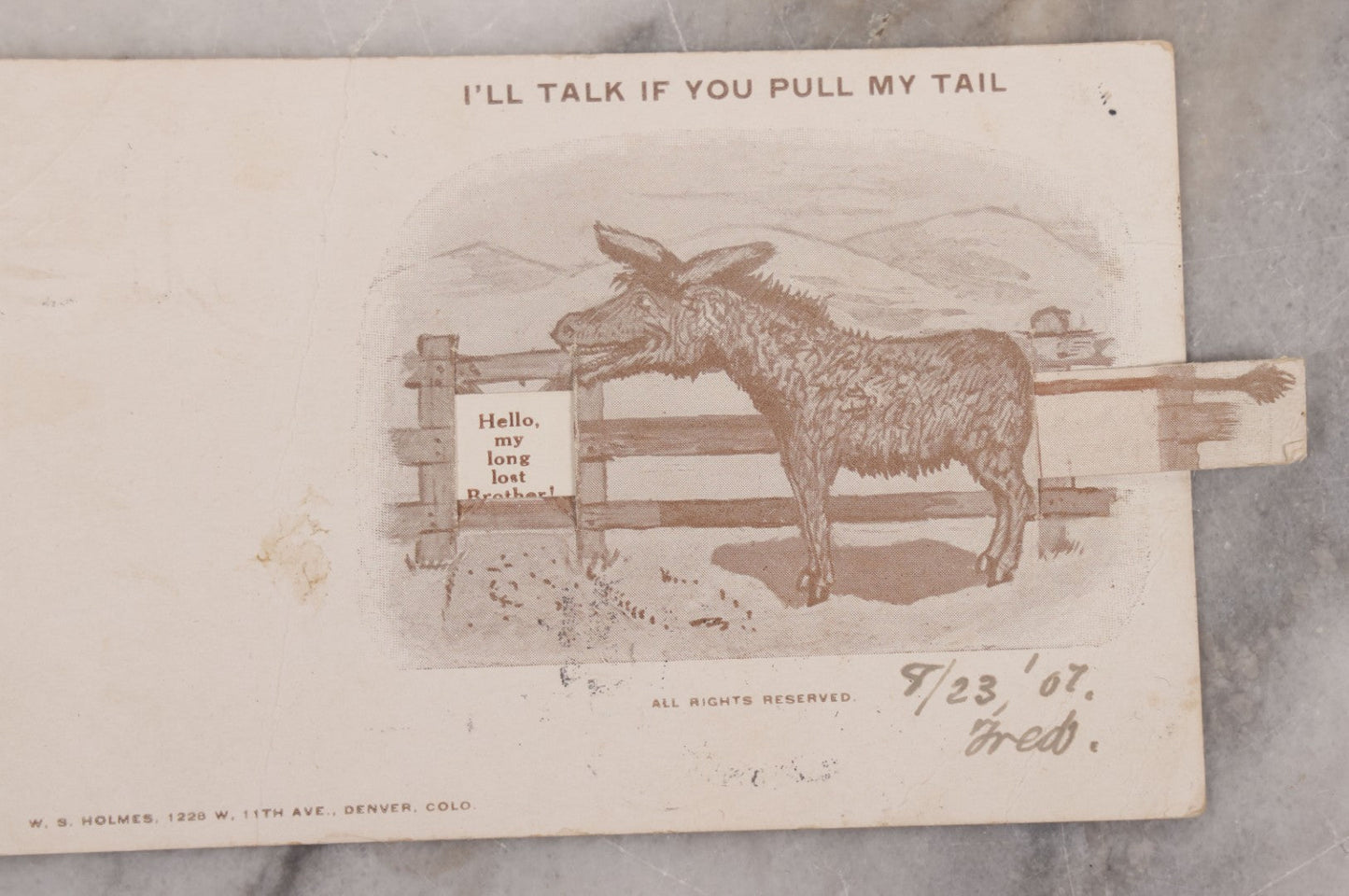 Lot 123 - Single Antique Mechanical Paper Postcard, Donkey, "I'll Talk If You Pull My Tail," Pulling Tail Reveals Message, "Hello My Long Lost Brother," W.S. Holmes, Publisher, Denver, Colorado, Signed Fred, 1907, Postmarked