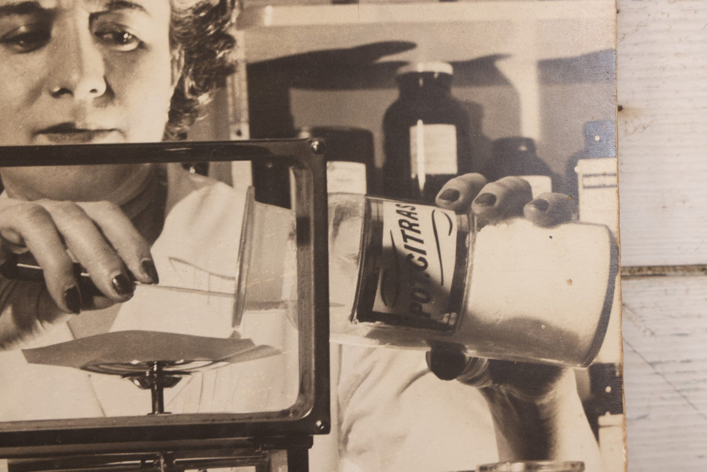 Lot 144 - Vintage Large Cardboard Mount Black And White Photograph Print Of Woman Pharmacist Measuring Drugs From Antique Glass Label Apothecary Jar, Many Drugs On Shelves In Background, 13-1/4" x 16-1/2"