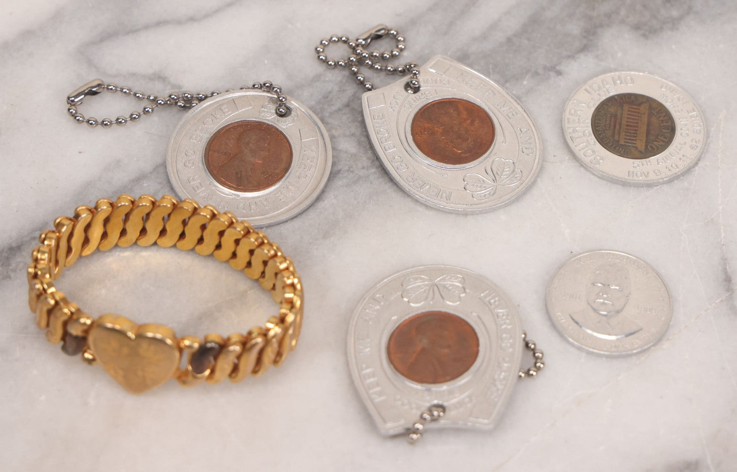 Lot 152 - Vintage Grouping Of Four  Souvenir Coin Dogtags, "Keep Me And Never Go Broke" Penny Souvenir, Shell's Coin Game Souvenir Coin, And Heart Locket Expanding Bracelet