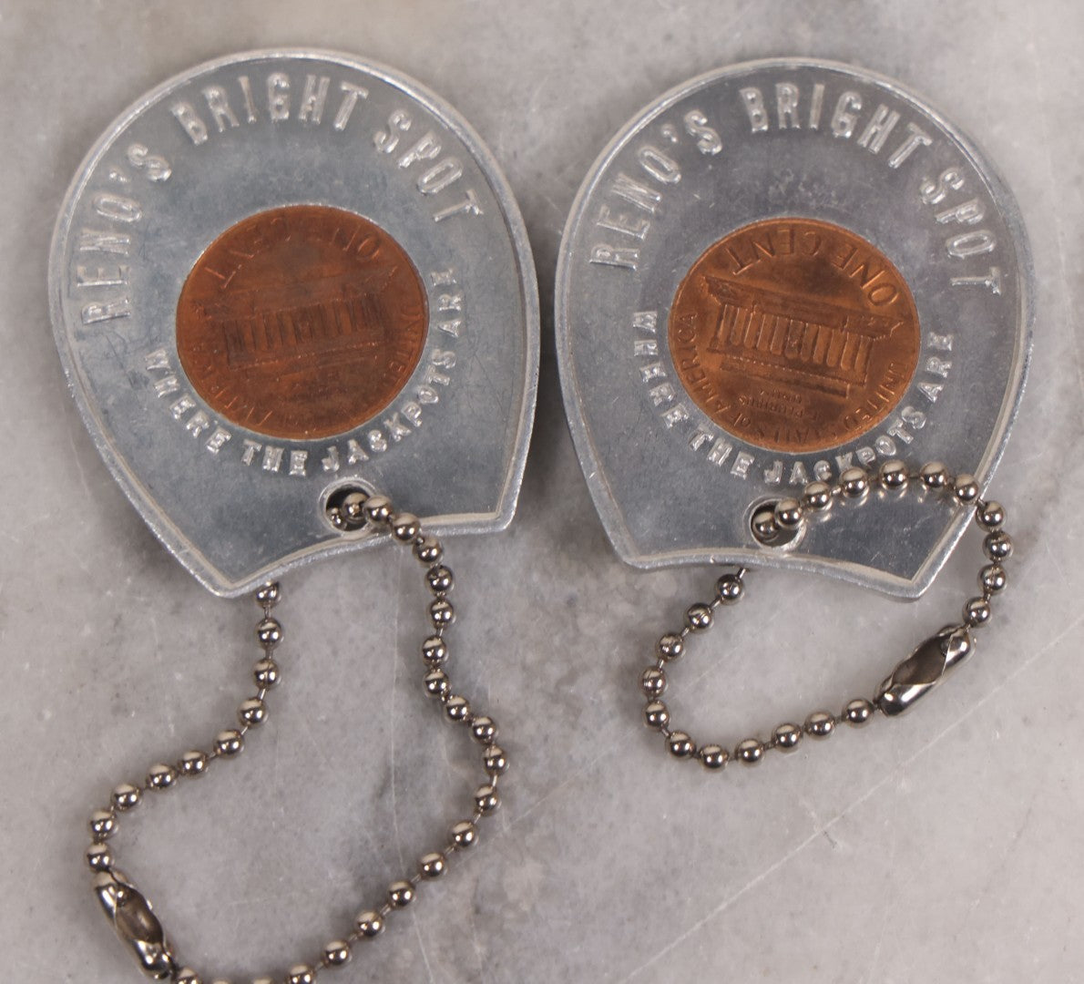 Lot 152 - Vintage Grouping Of Four  Souvenir Coin Dogtags, "Keep Me And Never Go Broke" Penny Souvenir, Shell's Coin Game Souvenir Coin, And Heart Locket Expanding Bracelet