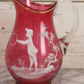 Lot 042 - Antique Mary Gregory Style Cranberry Glass Pitcher Hand Painted Enamel Decoration Of Boy Playing Hoop And Gold Trim, 10-1/8" H