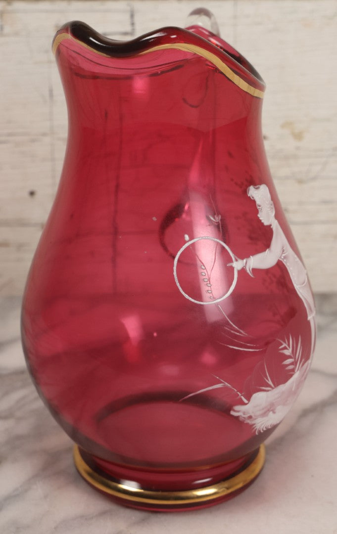 Lot 042 -  Antique Mary Gregory Style Cranberry Glass Pitcher Hand Painted Enamel Decoration Of Boy Playing Hoop And Gold Trim