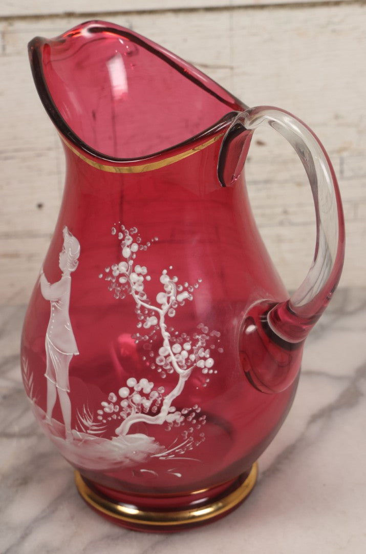 Lot 042 -  Antique Mary Gregory Style Cranberry Glass Pitcher Hand Painted Enamel Decoration Of Boy Playing Hoop And Gold Trim