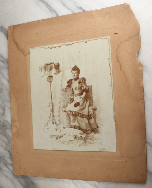 Lot 130 - Antique Boarded Photograph Of A Well Dressed Woman Posing On An Elaborate Set With Piano Lamp