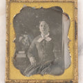 Lot 030 - Antique Uncased 1/6th Plate Daguerreotype Photograph Of A Young Woman Posing With A Table, Flowers, And Books, With Brass Mat And Preserver
