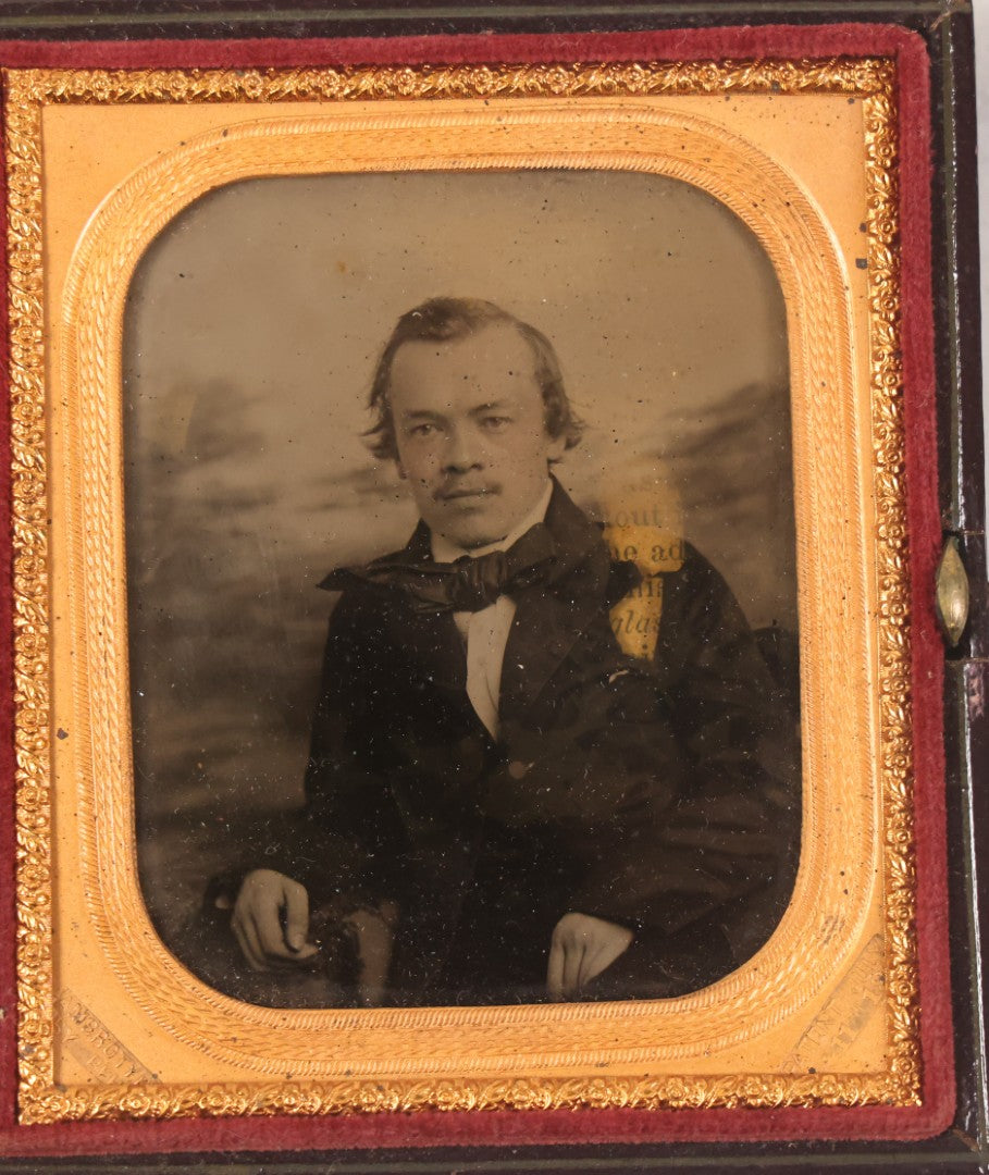 Lot 033 - Antique 1/6th Plate Ambrotype Photograph Of A Young Man With Mustache, Slight Smile, Photographed By I. Rehn, Philadelphia, With Note From Rehn In Case Regarding Care Of Ambrotypes, In Intact Leatherette Union Case, Note Loss To Black Varnish