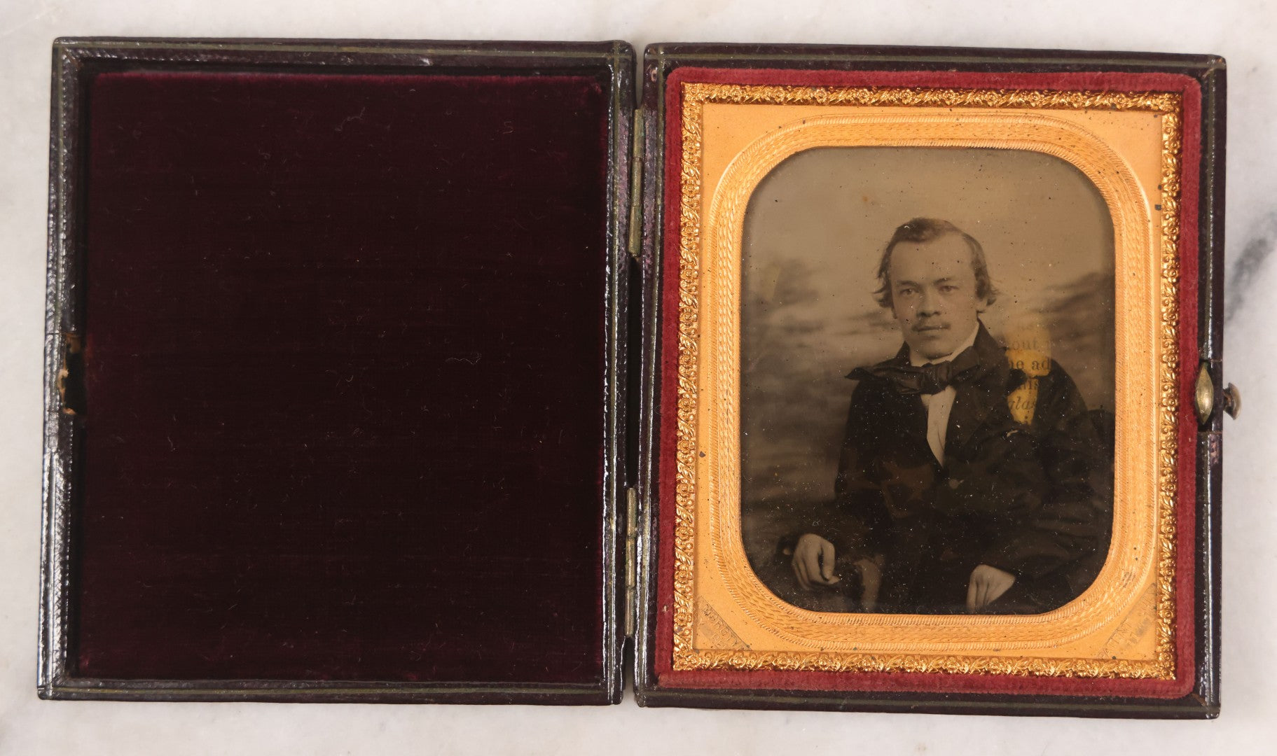 Lot 033 - Antique 1/6th Plate Ambrotype Photograph Of A Young Man With Mustache, Slight Smile, Photographed By I. Rehn, Philadelphia, With Note From Rehn In Case Regarding Care Of Ambrotypes, In Intact Leatherette Union Case, Note Loss To Black Varnish