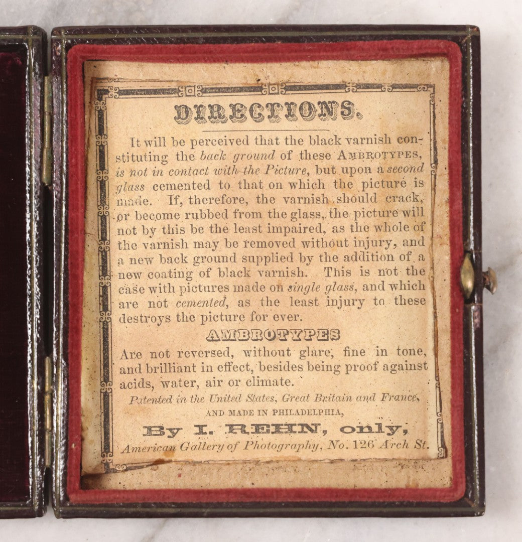 Lot 033 - Antique 1/6th Plate Ambrotype Photograph Of A Young Man With Mustache, Slight Smile, Photographed By I. Rehn, Philadelphia, With Note From Rehn In Case Regarding Care Of Ambrotypes, In Intact Leatherette Union Case, Note Loss To Black Varnish