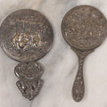 Lot 037 - Pair Of Vintage Embossed Pressed Metal Beveled Glass Hand Mirrors, Tavern & Festive Village Scenes, One Marked Denmark