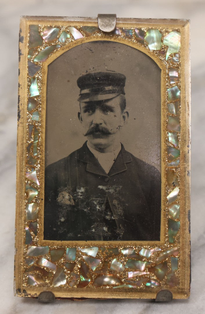 Lot 068 - Antique Tintype Photograph Of Man With Mustache Wearing Cap, In Period Reverse Painted Abalone And Gold Flake Beveled Glass Frame, 2-5/8" x 4-3/8"