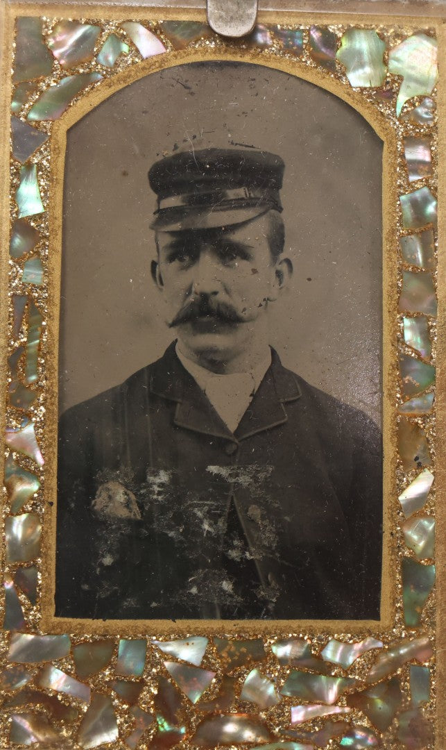 Lot 068 - Antique Tintype Photograph Of Man With Mustache Wearing Cap, In Period Reverse Painted Abalone And Gold Flake Beveled Glass Frame, 2-5/8" x 4-3/8"