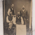 Lot 090 - Antique Tintype Photograph Of Four Well Dressed Men With Mustaches, One Man Holding Illegible Poster, Other Man Holding Pamphlet Or Book